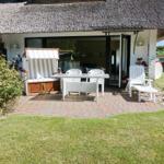 House with thatched roof and terrace with garden furniture.