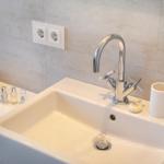 Waschbecken mit Armatur und Flaschen auf Ablagefläche