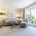Wohnzimmer mit Sofa, Sessel und Glastür zur Terrasse