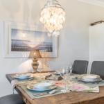 Esszimmer mit rustikalem Tisch, grauen Stühlen und moderner Deckenleuchte.