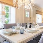 Dining room with set table, chandelier, and windows to the garden.
