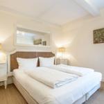 Bedroom with double bed, nightstands, and mirror on the wall.
