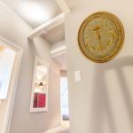 Hallway with gold-framed wall art, mirror, and doorways to bedroom and bathroom.