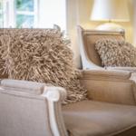 Two chairs with straw cushions and white wooden frames stand by a window.
