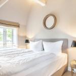 Bedroom with double bed, window, and round mirror on the wall.