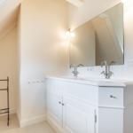 Bathroom with sink, mirror, and towel rack under sloped ceiling