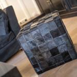 Black cowhide ottoman with cushions on wooden floor