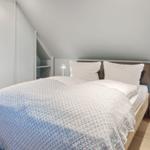 Schlafzimmer mit Doppelbett, Nachttisch und Kleiderschrank unter Dachschrägen.