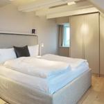 Schlafzimmer mit Bett, Kleiderschrank und Fenster.