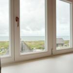 Durch das Fenster ist das Meer und eine grüne Landschaft mit Häusern sichtbar.