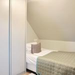 Schlafzimmer mit Dachschräge, Bett und Kleiderschrank.