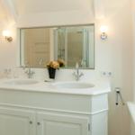 Doppelwaschbecken mit Spiegel und Dusche im Badezimmer.