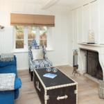 Wohnzimmer mit blauem Sofa, Kamin und Holzboden.
