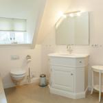 Badezimmer mit Waschbecken, Toilette, Badewanne und Spiegelschrank.