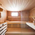 Wooden sauna with benches, bucket, and small window.