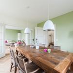 Dining area with wooden table and chairs, green wall and white ceiling