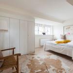 Bedroom with bed, wardrobe, and wooden chair on cowhide rug.