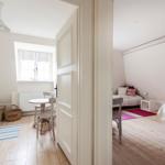 Room with wooden floor, bed, table and chairs. Window with curtain.