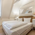 Schlafzimmer mit Doppelbett, zwei Nachttischen und Spiegel an der Wand.