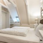 Schlafzimmer mit Doppelbett, Kleiderschrank und Dachschränken.