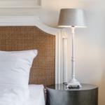 Schlafzimmer mit Bett, Nachttisch und Stehlampe.