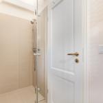 Dusche mit Glaswand, weiße Tür und Heizkörper