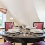 Runder Tisch mit Platz für vier Personen, Fenster und Schränke im Raum.