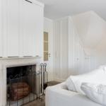 Wohnzimmer mit Kamin und weißem Sofa unter schrägem Dach