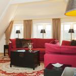 Living room with red sofa, rug, and windows.