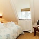 Bedroom with bed, TV, and window under sloped ceiling.
