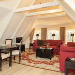 Living and dining area with red sofa, table and chairs under sloped ceilings.