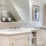 Badezimmer mit Waschbecken, Spiegel und Fenster