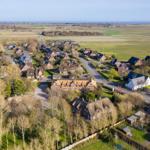 Dorf mit strohgedeckten Häusern und grünen Feldern am Meer