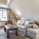 Wohnzimmer mit Sofa, Couchtisch und Fenster mit Vorhängen.