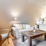 Wohnbereich mit Sofa, Sessel und Küchenzeile unter Dachschrägen.