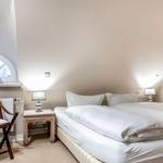 Schlafzimmer mit Doppelbett, Nachttisch und Stuhl unter schrägen Dachbodenwänden.