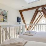 Schlafzimmer mit Dachschrägen, weißem Geländer und Poster an der Wand.