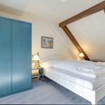 Schlafzimmer mit Doppelbett, blauem Schrank und Holzbalken an der Decke.