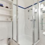 Badezimmer mit Dusche, Waschbecken und Regal