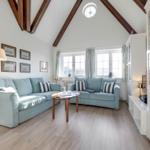 Wohnzimmer mit zwei hellblauen Sofas, Holzboden und hohen Deckenbalken.