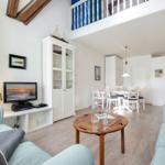 Wohn- und Essbereich mit Holztisch, Sofa und Treppenaufgang zur oberen Etage.