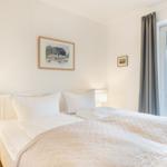 Schlafzimmer mit Bett, Lampen und Fensterblick auf Garten
