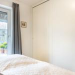 Schlafzimmer mit Bett, Kleiderschrank und Fenster zum Garten.