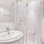 Badezimmer mit Dusche, Waschbecken und Spiegel.