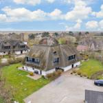 Haus mit Strohdach, Garten und Blick auf die Landschaft.