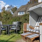 Backyard with garden furniture and beach chair. A thatched-roof house in the background.