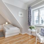Room with two beds, window, chair, and flowers