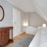 Room with two beds, wooden floor, and antique dresser under sloped ceiling.
