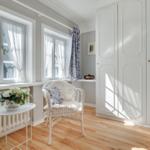 Room with two windows, white closet, and chair with fur cushion.