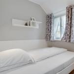 Bedroom with bed, window, and wall shelf.